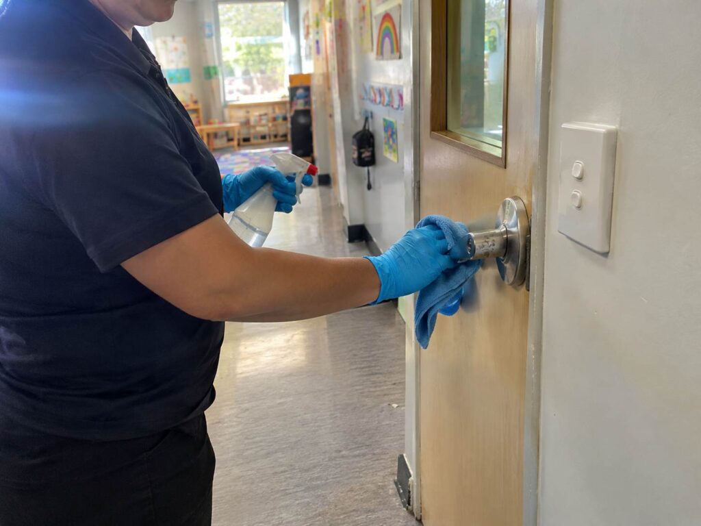 Childcare cleaners sanitising a high touch door handle during a Sydney centre clean