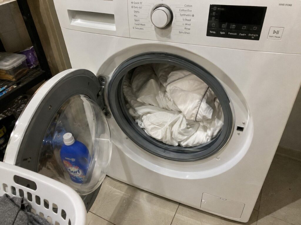 Loading linen sheets into a washing machine on a gentle cycle