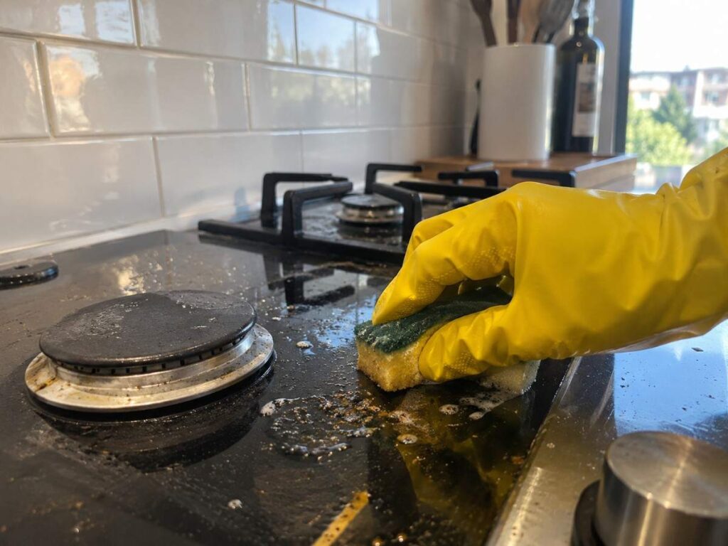 Scrubbing a stovetop as part of a kitchen deep cleaning service checklist