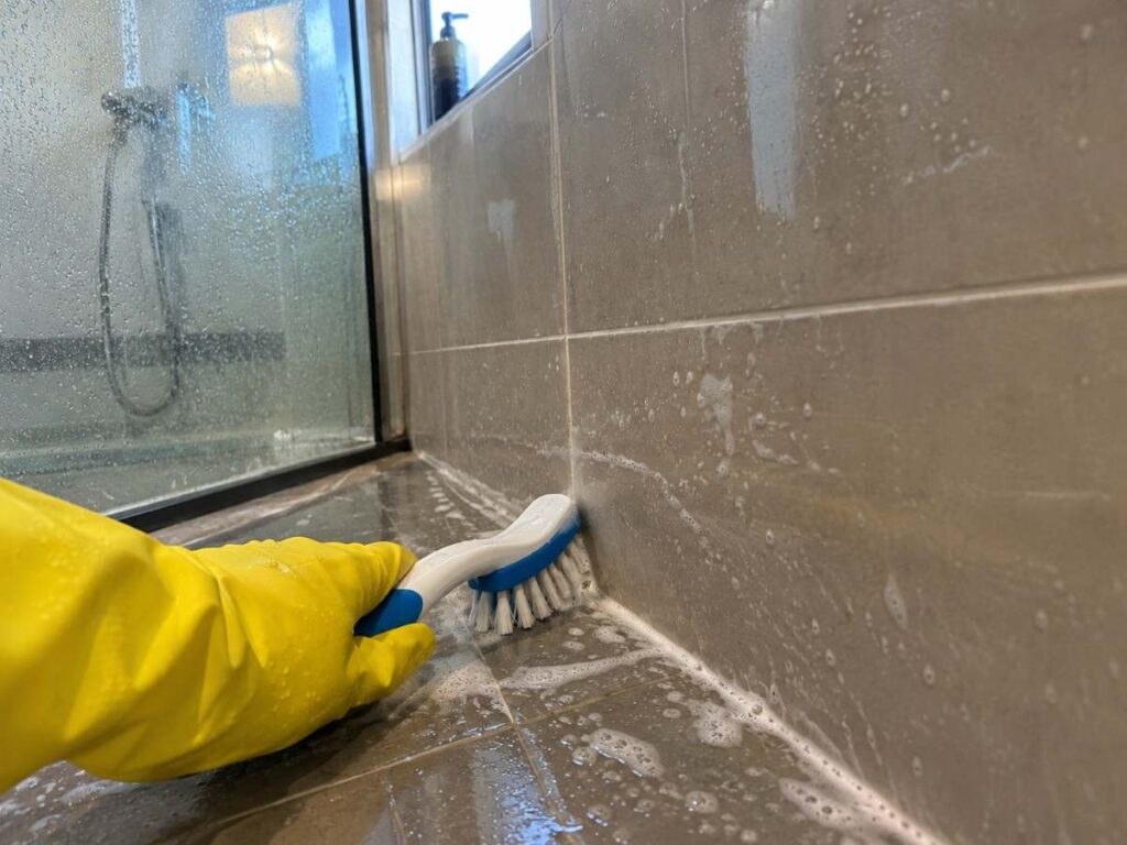Scrubbing shower grout during a bathroom deep clean service