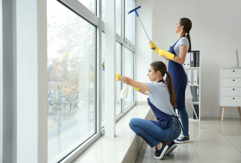 A cleaner washing a window until it is streak-free