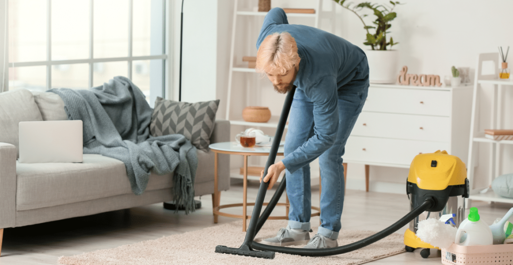 A cleaner vacuuming the carpet in an apartment living room