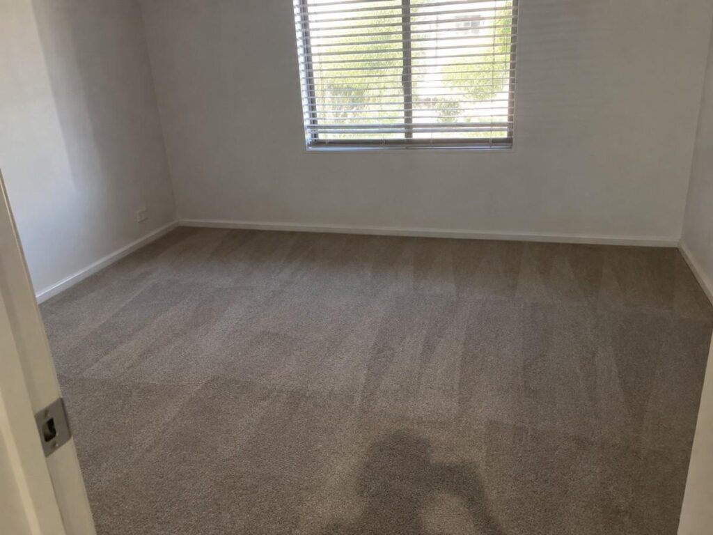 Empty bedroom with vacuumed carpet and clean skirting boards after a move-out cleaning