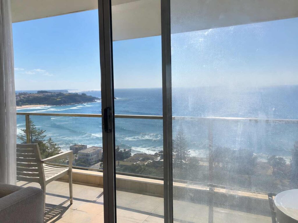 Balcony glass balustrade with salt film overlooking the ocean at a common area Sydney