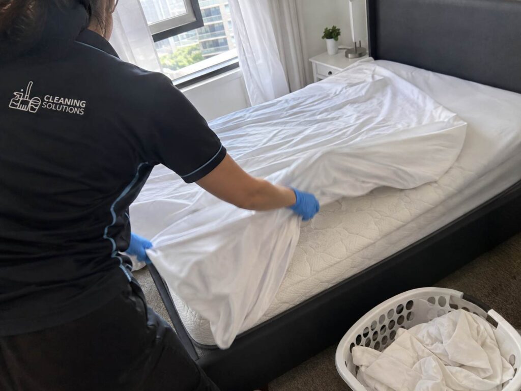 Cleaner stripping used bed linen during a same day Airbnb turnover in Sydney