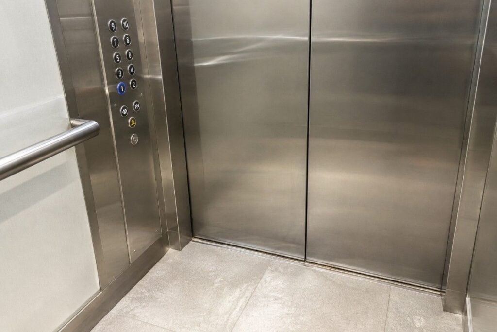 Close view of a clean lift door track and buttons in a high-rise apartment tower